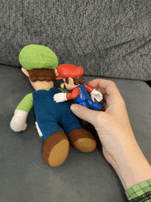 a person holding a stuffed mario and luigi