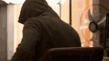 a man in a hooded jacket is sitting at a desk with a laptop .