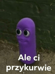 a purple worm with big eyes is standing in front of a brick wall with the words `` ale ci przykurwie '' .