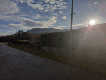 the sun is shining through the clouds over a fenced in area