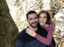 a man and woman are posing for a picture and the woman is wearing a ring on her finger