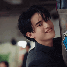 a young man in a suit is smiling while leaning against a wall with a blue star on it