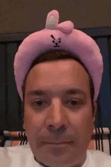 a man is wearing a pink headband with a rabbit on it .