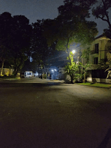 a residential street at night with a few houses and trees