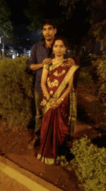 a man and woman pose for a picture in a park