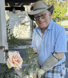 an elderly man wearing a hat and gloves is holding a rose