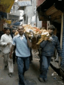 a group of men are carrying a large load down a street in front of a sign that says ' a ' on it