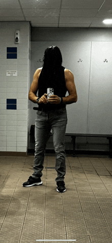 a man taking a picture of himself in a locker room with a sign that says no smoking