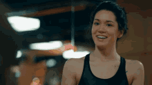 a woman in a black tank top is smiling