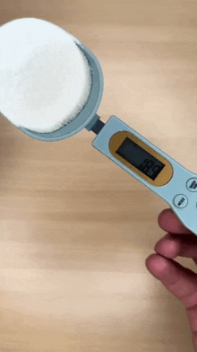 a person is holding a measuring spoon with a digital display that says 49.9 on it