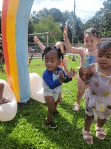 a group of young children are playing in a rainbow inflatable pool .