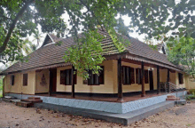 a very old house with a large porch and trees in the background .