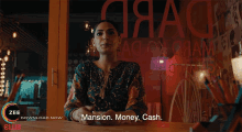 a woman sitting at a table with the words mansion money cash written on the bottom