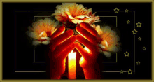 a person is holding a lit candle in their hands with flowers in the background .