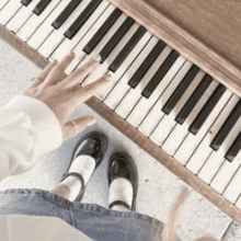 a person is playing a piano with their hands and feet in front of it .