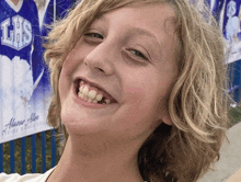 a young boy is smiling in front of a sign that says lhs