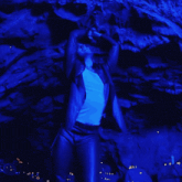 a man in a leather jacket stands in front of a blue wall