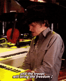 a man in a cowboy hat is playing a keyboard with the words " and the troops will bring the freedom " above him