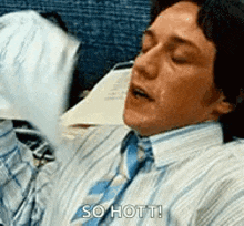 a man in a striped shirt and tie is holding a piece of paper in his hand and saying so hot !