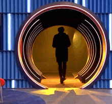 a silhouette of a man is walking through a circular tunnel