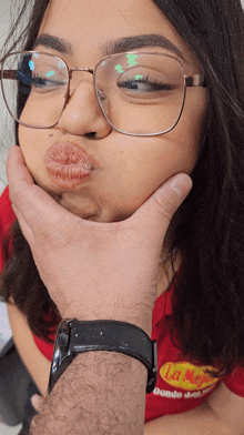 a woman wearing glasses is being kissed by a man wearing a watch that says la mejor