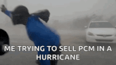a person is trying to sell a pcm in a hurricane while a car is driving by .