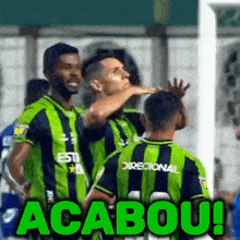 a group of soccer players wearing green and black uniforms with the words " acabou " on the bottom right