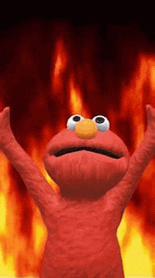 elmo from sesame street is standing in front of a fire with his arms up .