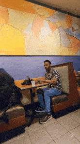 a man sits in a booth at a table with a laptop on it