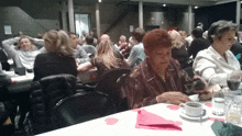 a woman sits at a table with a cup of coffee in front of her