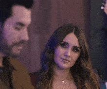 a man and woman are standing next to each other and the woman is wearing a necklace