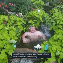 a man is taking a bath in a pond surrounded by plants and flowers .