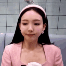 a close up of a woman wearing a pink headband and a pink shirt .
