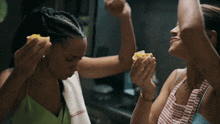 two women are eating food in a kitchen and one of them is holding a piece of food in her hand