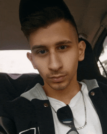 a young man wearing a black jacket and a white shirt is sitting in a car