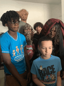 a boy wearing a blue shirt that says race stands in front of a group of people