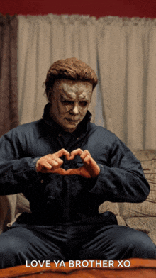 a man in a mask is making a heart with his hands