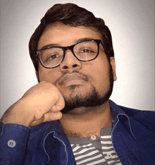 a man with a beard and glasses is wearing a striped shirt and a blue shirt .