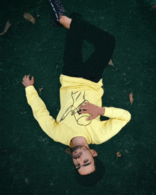 a man in a yellow shirt is laying on his back on the ground