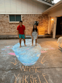 a man and a woman standing in front of a chalk drawing of a whale and the words " make yourself "