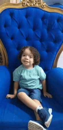 a little boy is sitting in a blue chair and smiling