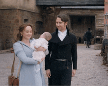 a man and a woman holding a baby in front of a building that says ' a ' on it