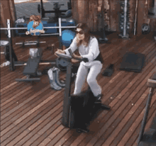 a woman is riding an exercise bike on a wooden deck in front of a sign that says a família