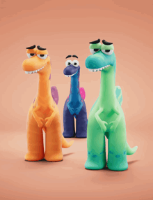 three cartoon dinosaurs are standing next to each other on a brown background