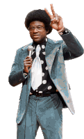 a man in a suit is holding a microphone and making a peace sign