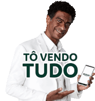 a man in a white suit is holding a phone and says to vendo tudo