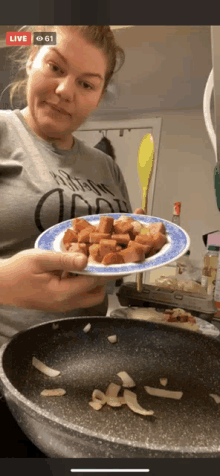 a woman is holding a plate of food in front of a pan while cooking .