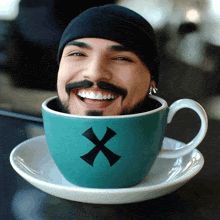 a man with a beard and mustache is smiling in a blue cup with a cross on it