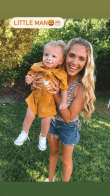 a woman is holding a baby with icing on his face and a little man sticker