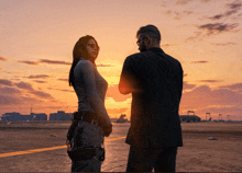 a man and a woman stand on a runway at sunset